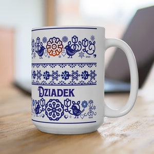 May include: White ceramic mug with a blue floral and bird design. The mug features the word "Dziadek" in blue lettering. The design includes various floral and bird motifs, creating a decorative pattern around the mug.
