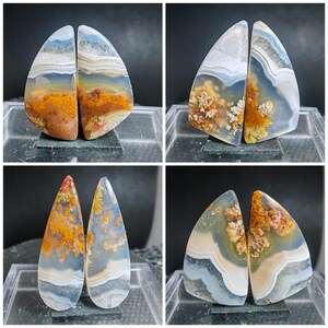 May include: Four pairs of polished agate stones. Each pair is cut to reveal unique patterns of orange, brown, white, and blue hues. The stones have a smooth, glossy finish, showcasing the natural beauty of the mineral formations.