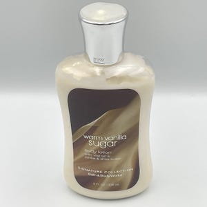 May include: A bottle of Bath & Body Works Warm Vanilla Sugar body lotion. The lotion is in a clear bottle with a silver cap. The label features the text "Warm Vanilla Sugar" and "Signature Collection". The bottle contains 8 fl oz / 236 mL.