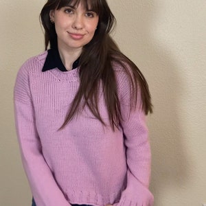 以下が含まれることがあります： 長袖の薄い紫色のセーターを着た女性。セーターは少し短く、ゆったりとしたフィット感です。