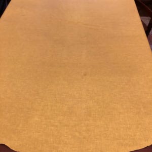 Op de afbeelding: Een ronde, gele tafelkleed met een licht getextureerd oppervlak.