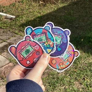May include: Three colorful holographic stickers featuring a cartoon turtle design. Each sticker has a different color scheme and features a unique design with stars and other details. The stickers are perfect for adding a touch of whimsy to laptops, water bottles, or journals.