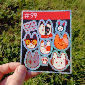 May include: A holographic sticker sheet featuring nine cartoon cat faces with various expressions and accessories. The sticker sheet has a red header with the number "#99" in white. The cats are in different colors, including orange, gray, and white.