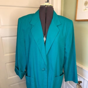 Könnte beinhalten: Ein blauer Blazer mit einem einzigen Knopfverschluss, zwei Eingrifftaschen und langen Ärmeln. Der Blazer befindet sich auf einem Mannequin.