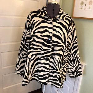May include: A black and white zebra print button-up jacket with long sleeves.