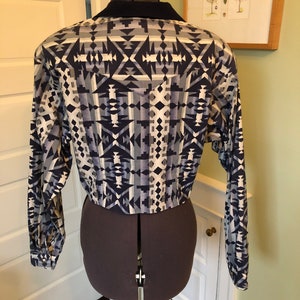 May include: A long-sleeved shirt with a geometric pattern in shades of blue, white, and gray. The shirt has a pointed collar and a button-up front.