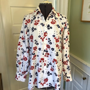 Puede incluir: Una camisa blanca de manga larga con botones y estampado floral en rojo, azul y blanco.