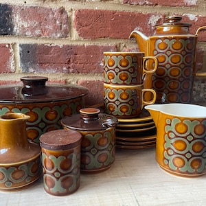 May include: A vintage brown and green patterned ceramic tea set with a teapot, creamer, sugar bowl, salt and pepper shakers, and cups and saucers.