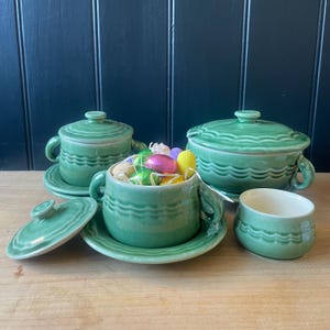 May include: Set of four green ceramic soup bowls with lids. The bowls have a wavy design and are filled with colourful chocolate eggs.