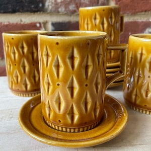 May include: Set of four brown ceramic coffee mugs with matching saucers. The mugs and saucers feature a diamond pattern.