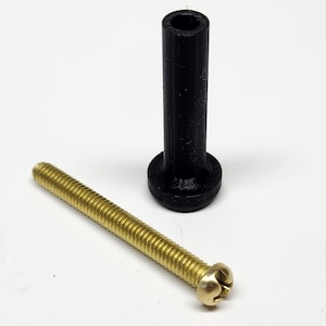May include: A black plastic cylindrical component with a wide base and a brass screw with a slotted head. The screw has a threaded shaft and a rounded head. The items are on a white surface.