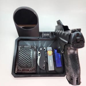 Pode incluir: Uma bandeja preta com um espelho, uma carteira, uma faca de bolso, um isqueiro e uma pistola. A bandeja tem uma superf&iacute;cie texturizada e as palavras "ALIAS" est&atilde;o impressas na bandeja.