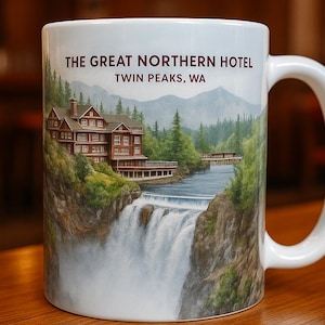 May include: White ceramic mug featuring a colourful image of a waterfall and a building with the text "The Great Northern Hotel Twin Peaks, WA".