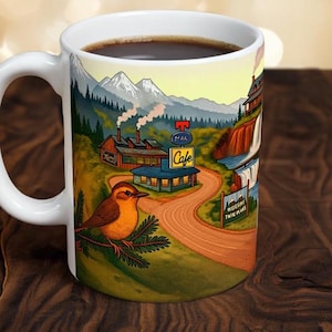 May include: White ceramic coffee mug featuring a scenic illustration of a cafe, waterfall, and mountains. A brown and orange bird sits on a branch. The mug is filled with dark coffee.