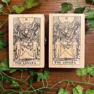 May include: Two rectangular light-colored wooden boxes featuring a black ink illustration of The Lovers tarot card. Each box displays the Roman numeral VI at the top and the text THE LOVERS at the bottom, depicting two figures and an angel.