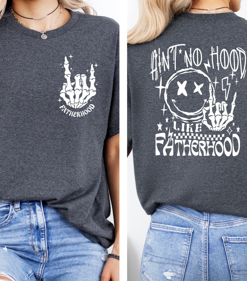 K&ouml;nnte beinhalten: Dunkelgraues T-Shirt mit wei&szlig;en Grafikdesigns. Die Vorderseite zeigt eine Skeletthand in einer Rock-and-Roll-Geste mit dem Wort "FATHERHOOD". Auf der R&uuml;ckseite befindet sich ein Smiley mit durchgestrichenen Augen, Blitzen und dem Satz "AIN'T NO HOOD LIKE FATHERHOOD".