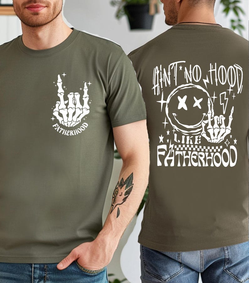 K&ouml;nnte beinhalten: Olivgr&uuml;nes T-Shirt mit einer wei&szlig;en Skeletthand-Grafik, die eine Rock'n'Roll-Handbewegung ausf&uuml;hrt, mit dem Wort "FATHERHOOD" darunter. Auf der R&uuml;ckseite des Shirts steht der Text "AIN'T NO HOOD LIKE FATHERHOOD" mit einem Smiley und Blitzen.
