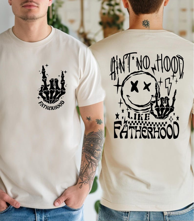 K&ouml;nnte beinhalten: Cremefarbene T-Shirts mit schwarzen Grafikdesigns. Eines zeigt eine Skeletthand mit dem Wort "FATHERHOOD". Das andere hat ein Smiley, einen Blitz und den Text "AIN'T NO HOOD LIKE FATHERHOOD".