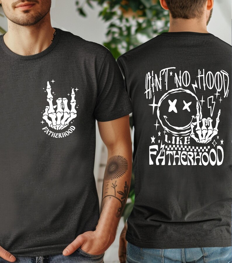 K&ouml;nnte beinhalten: Zwei dunkelgraue T-Shirts mit wei&szlig;en Grafikdesigns. Ein Shirt zeigt eine Skeletthand mit dem Wort "FATHERHOOD". Das andere Shirt hat den Text "AIN'T NO HOOD LIKE FATHERHOOD" mit einem Smiley und einer Skeletthand.