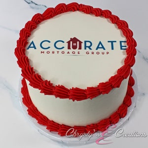 May include: A white cake with red frosting and a printed logo that says "Accurate Mortgage Group" on top.