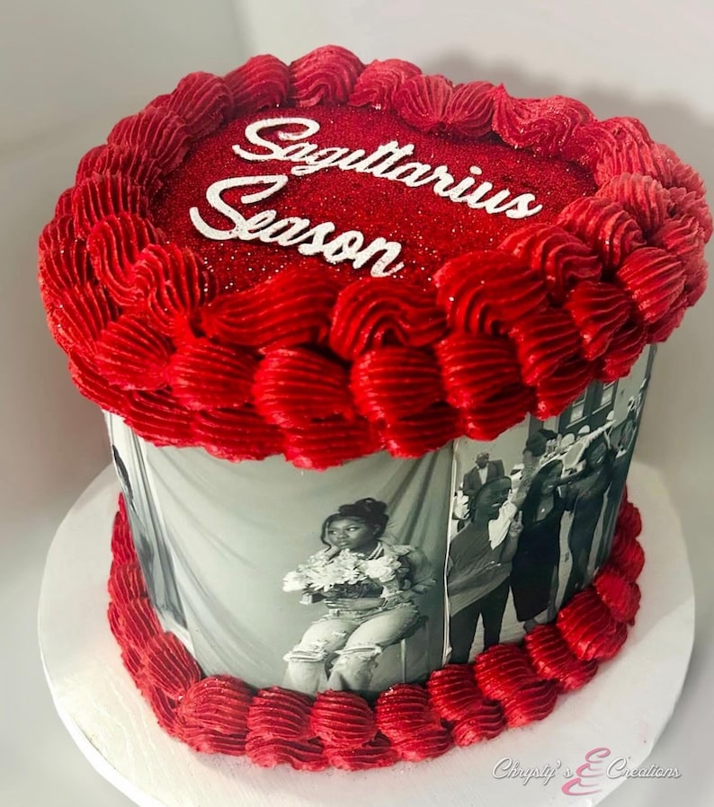 May include: A round cake with red frosting and the words "Sagittarius Season" in white. The cake is decorated with a red frosting border and a black and white photo wrap. The cake sits on a white cake board.