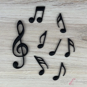 May include: A set of black musical note cake toppers, including a treble clef and several different note shapes.