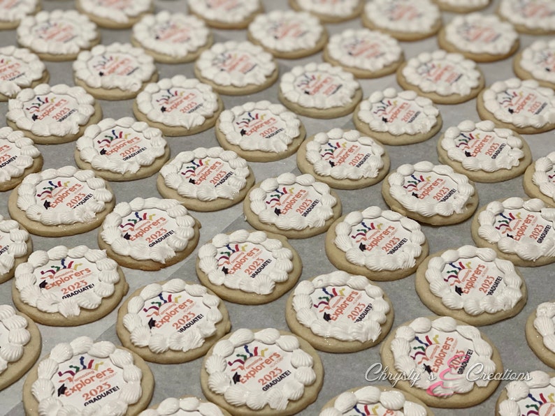 May include: A tray of decorated sugar cookies with white frosting and colorful designs. The cookies are decorated with the text "Explorers 2023 Graduate!"