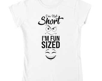 Puede incluir: Camiseta blanca con texto negro que dice "I'm Not Short I'm Fun Sized" con una cara frunciendo el ceño sobre el texto y una cara sonriente debajo del texto.