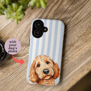 May include: A phone case featuring a light blue and white striped pattern with a portrait of a golden-brown dog. The text "with your dog's photo" is displayed on a pink circle.