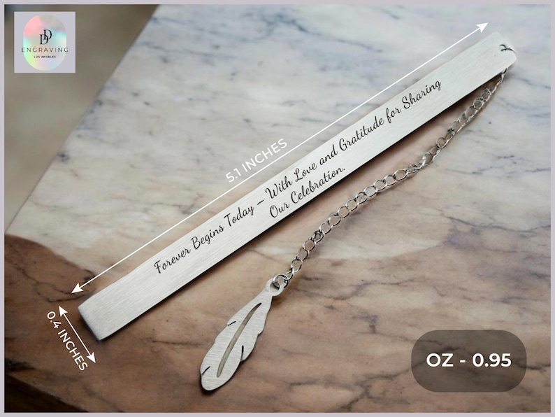 May include: Silver bookmark with a feather charm and the inscription "Forever Begins Today - With Love and Gratitude for Sharing Our Celebration." The bookmark is 5.1 inches long and 0.4 inches wide and weighs 0.95 ounces.