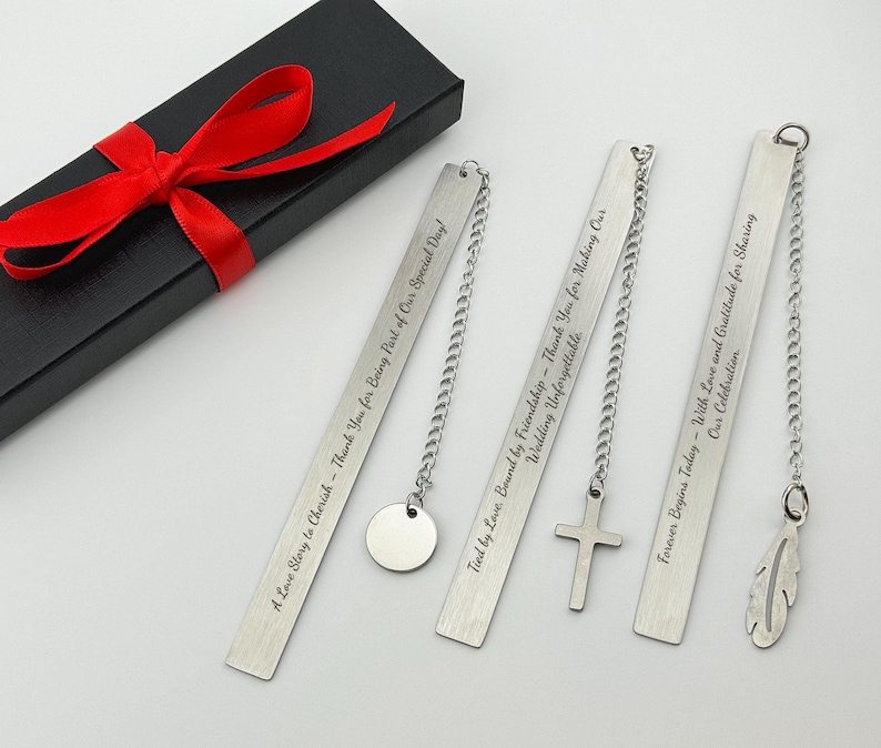 May include: Four silver bookmark chains with personalized engraved messages. The bookmarks feature a circle, cross, feather, and a blank space. The bookmarks are packaged in a black box with a red ribbon.
