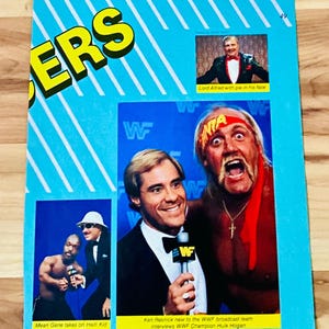 May include: A vintage magazine page with a blue background and white diagonal stripes. It features images of wrestlers and commentators, including Hulk Hogan and Mean Gene. Text includes "ERS" and "WWF Magazine August/September 86".