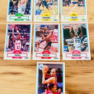 May include: A collection of seven basketball trading cards featuring professional players. The cards display action shots of players like Larry Bird, Tim Hardaway, and Charles Barkley. Each card has the player's name and position.