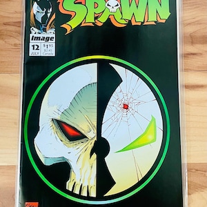 May include: A comic book cover featuring Spawn, a superhero with a skull-like face. The cover is black with a green circle around a split image of Spawn's face. The top half of the image is white with a red eye, and the bottom half is green with a green eye. The comic book is titled "Spawn" and is issue number 12.