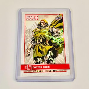 May include: A Marvel 2021-22 Annual trading card featuring Doctor Doom. The card shows Doctor Doom in a green hooded cloak, with green energy emanating from his hand. The card is in a protective sleeve.