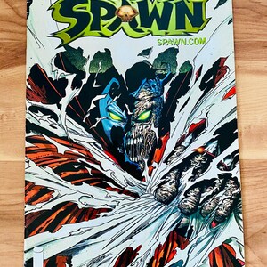 May include: A Spawn comic book, issue 101, titled The Epilogue to Issue 100. The cover features a central character with a blue and skeletal face, glowing green eyes, and a tattered red cape, emerging from a white, torn background.