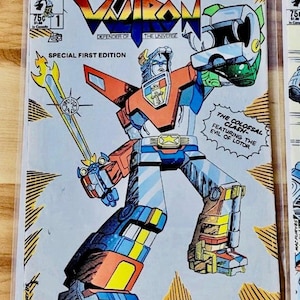 May include: Voltron comic book cover featuring a robot warrior in red, blue, and yellow. The comic is labeled "Special First Edition" with the text "Defender of the Universe". The cover also includes the text "The Colossal Clash Featuring the Evil of Lotor".
