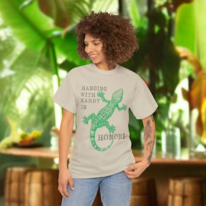 May include: A light beige t-shirt with a green gecko graphic and the text "HANGING WITH HARRY IN HONORE".