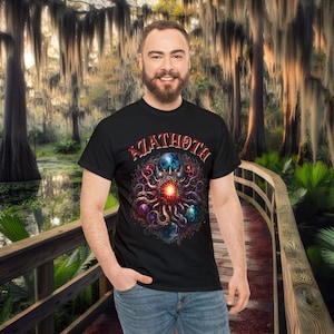 May include: Black t-shirt with a graphic print of a multi-colored, cosmic, tentacled creature with the word "Azathoth" in red lettering.