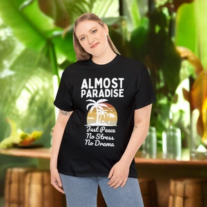 May include: Black t-shirt with a white graphic of palm trees and a sunset. The text "Almost Paradise" is above the graphic and the text "Just Peace No Stress No Drama" is below the graphic.