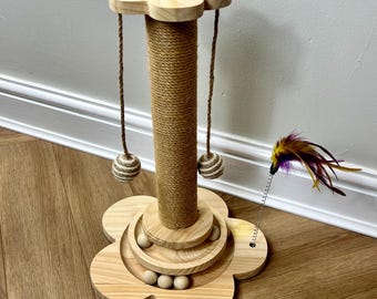 May include: A wooden cat scratching post with a flower-shaped base and a sisal-covered scratching post. The base has a ring of wooden balls that can be moved around. There is a dangling toy with feathers attached to the post.