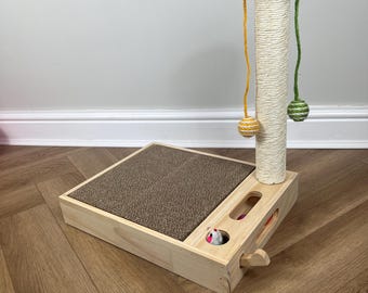 May include: A wooden cat scratching post with a sisal-covered scratching post and a platform with a scratching surface. The post has three dangling toys with colorful balls at the end of each string.