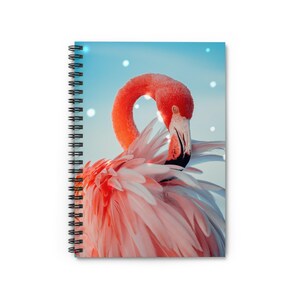 May include: Spiral-bound notebook featuring a vibrant image of a flamingo. The flamingo has pink feathers, a curved neck, and a black beak. The background is a light blue with white dots.