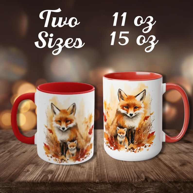 May include: Two white ceramic mugs with red interiors and handles. Each mug features a watercolor painting of a fox and a baby fox surrounded by autumn leaves. The text "Two Sizes" and "11 oz 15 oz" is displayed above the mugs.
