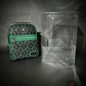 Puede incluir: Una mochila negra y verde con un patrón acolchado y una correa de cadena plateada. La mochila tiene una cremallera verde y un parche verde con las palabras "Harry Potter" y "Tom Riddle" en él. La mochila también tiene un parche verde con las palabras "Slytherin" y un logotipo de serpiente.