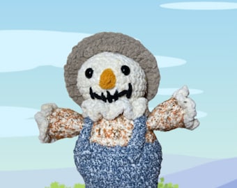 May include: A crocheted Scully Scarecrow pattern with a white and brown body, blue overalls, and a gray hat. The scarecrow is standing in a field with a small house in the background.