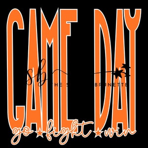 May include: Black background with the words "GAME DAY" in large orange block letters outlined in white. Below, the words "go fight win" are written in a script font with star accents. The text "THE S BRUNETTE" is also present.