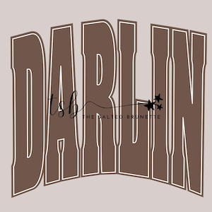 Peut inclure: Graphisme avec le mot "DARLIN" en gras, marron, avec un contour blanc. Le texte "tsb" et "THE SALTED BRUNETTE" sont également présents, ainsi que trois petites étoiles, le tout dans une palette de couleurs neutres.