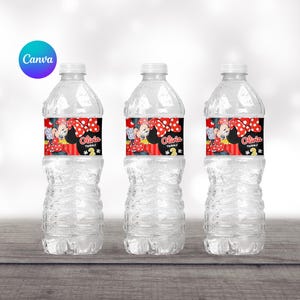 Op de afbeelding: Drie doorzichtige plastic waterflessen met zwarte en rode Minnie Mouse-thema labels. De labels tonen Minnie Mouse met een rode strik en stippen. De tekst op de labels luidt "Olivia wordt 2".