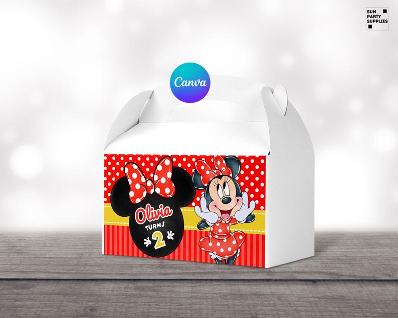 Op de afbeelding: Rode en witte traktatie doos met een Minnie Mouse ontwerp. De doos heeft een gele handvat en zegt "Olivia wordt 2" op de voorkant.